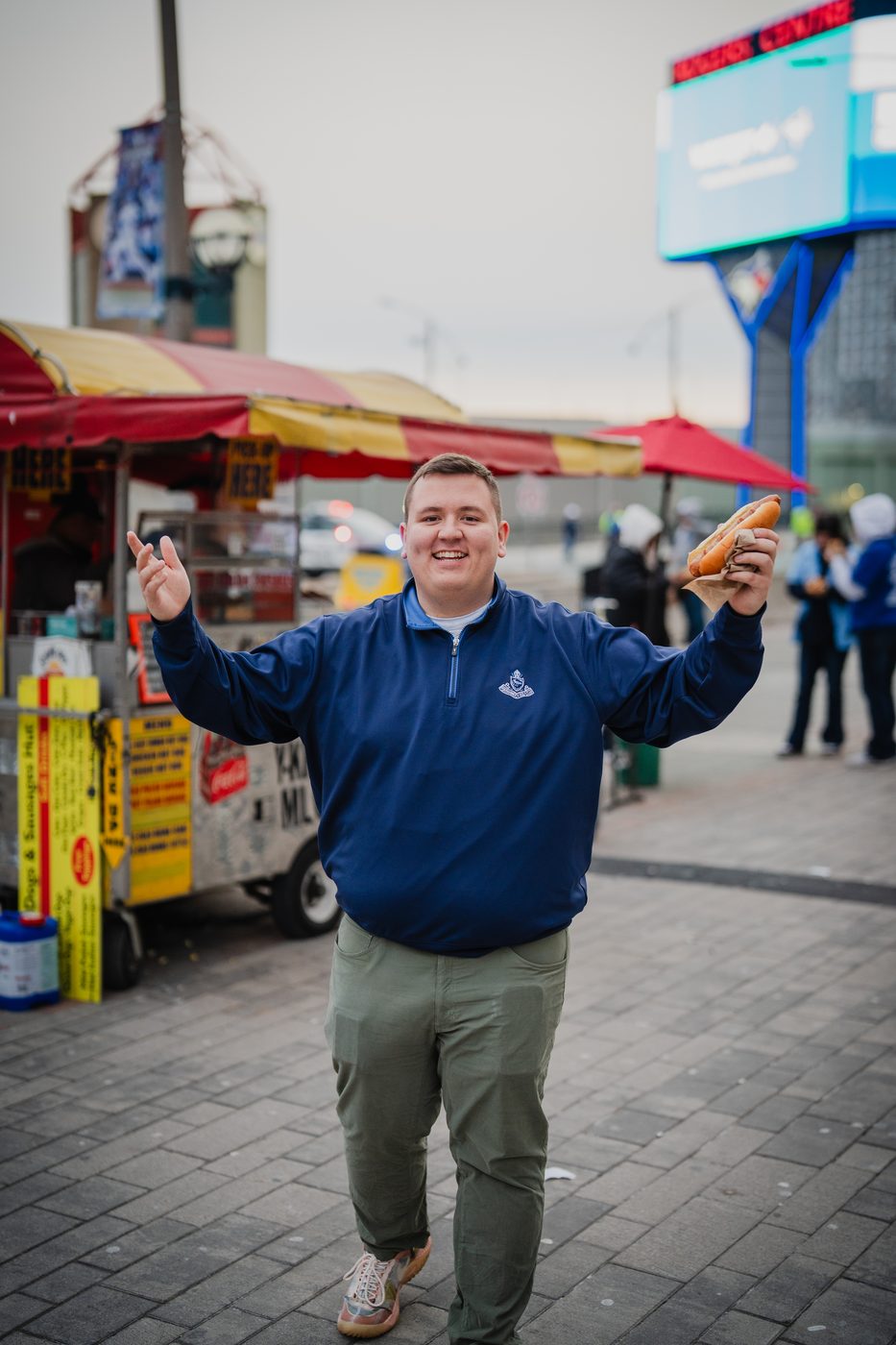 Robert Greeley outside Rogers Centre in Toronto, holding a hot dog from a street cart